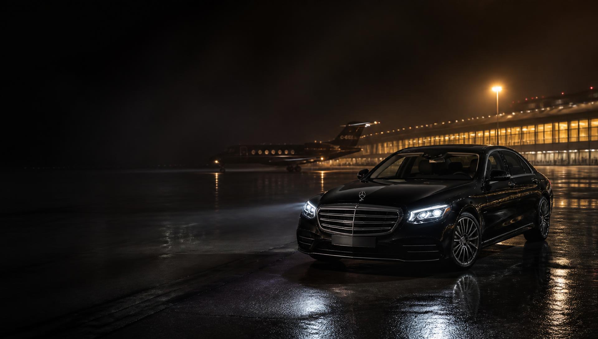 Chauffeur assisting a client into a black Mercedes S-Class beside a private jet